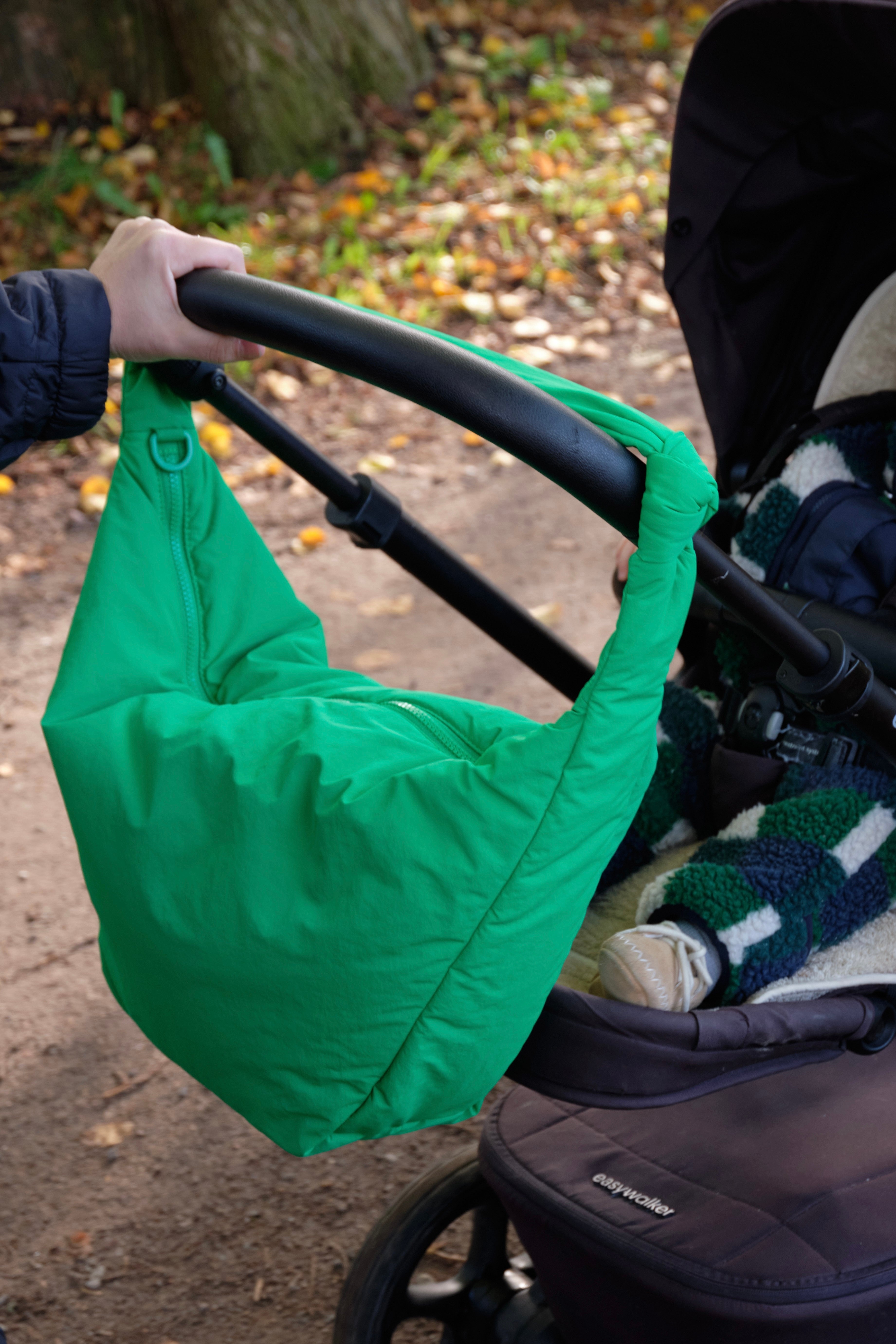 Grüne LUKKILY Nylon Wickeltasche seitlich am Kinderwagen befestigt, mit praktischen Kinderwagen-Straps für unterwegs.