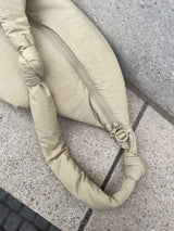 Nahaufnahme des Materials der Wickeltasche aus wasserabweisendem, beigen Nylon mit farblich passendem Reiverschluss und Öse zur Anbringung der Kinderwagenstraps