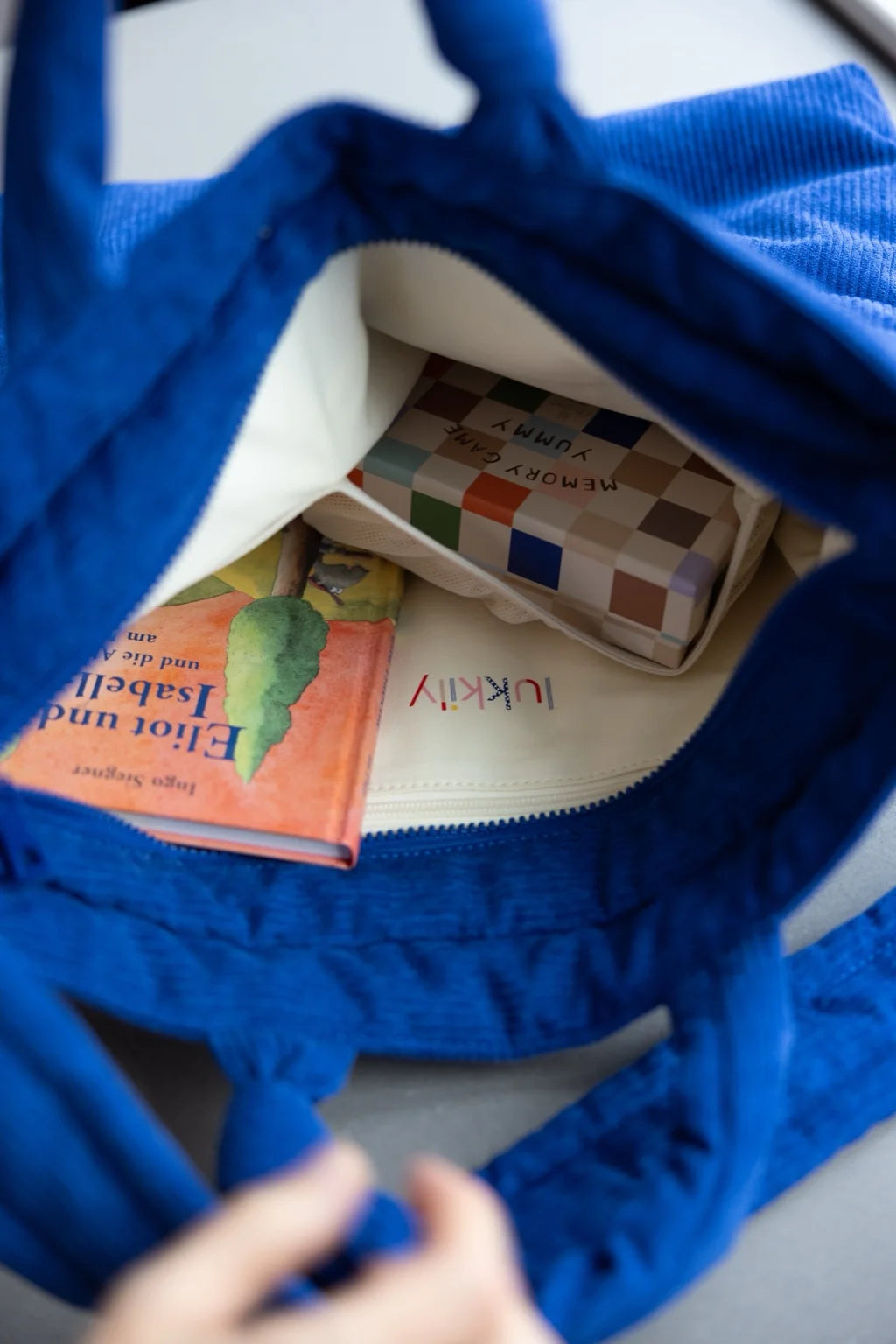 Blaue Lukkily Tote Bag - Innenansicht der Mombag mit praktischen elastischen Fächern und einem Fach mit Reißverschluss für Wertsachen sowie buntem lukkily Logo