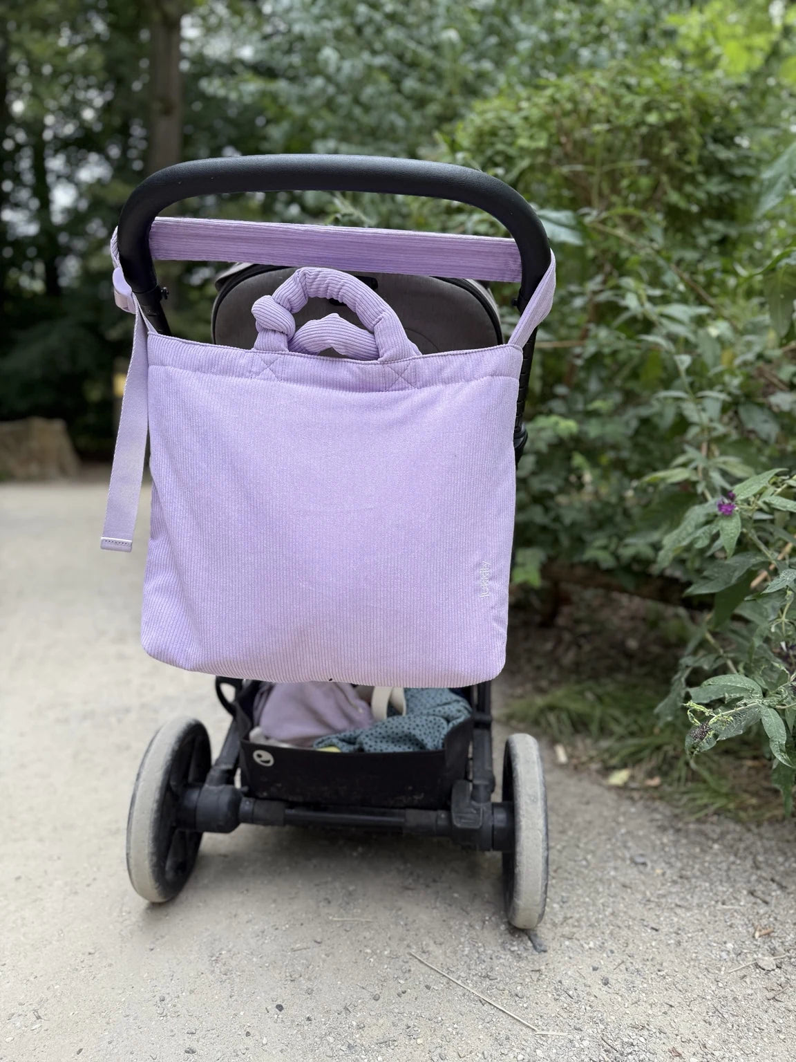 Wickeltasche aus weichem, lavendelfarbenem Cord am Kinderwagenbügel