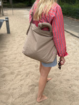 Lukkily Tote Bag taupe - sportive Mombag im monochromen beigen Look lässig auf den Rücken geschoben um die Hände auf dem Spielplatz frei zu haben