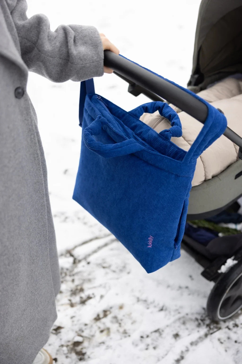 Blaue Lukkily Mombag -  Wickeltasche aus Cord am Kinderwagen befestigt