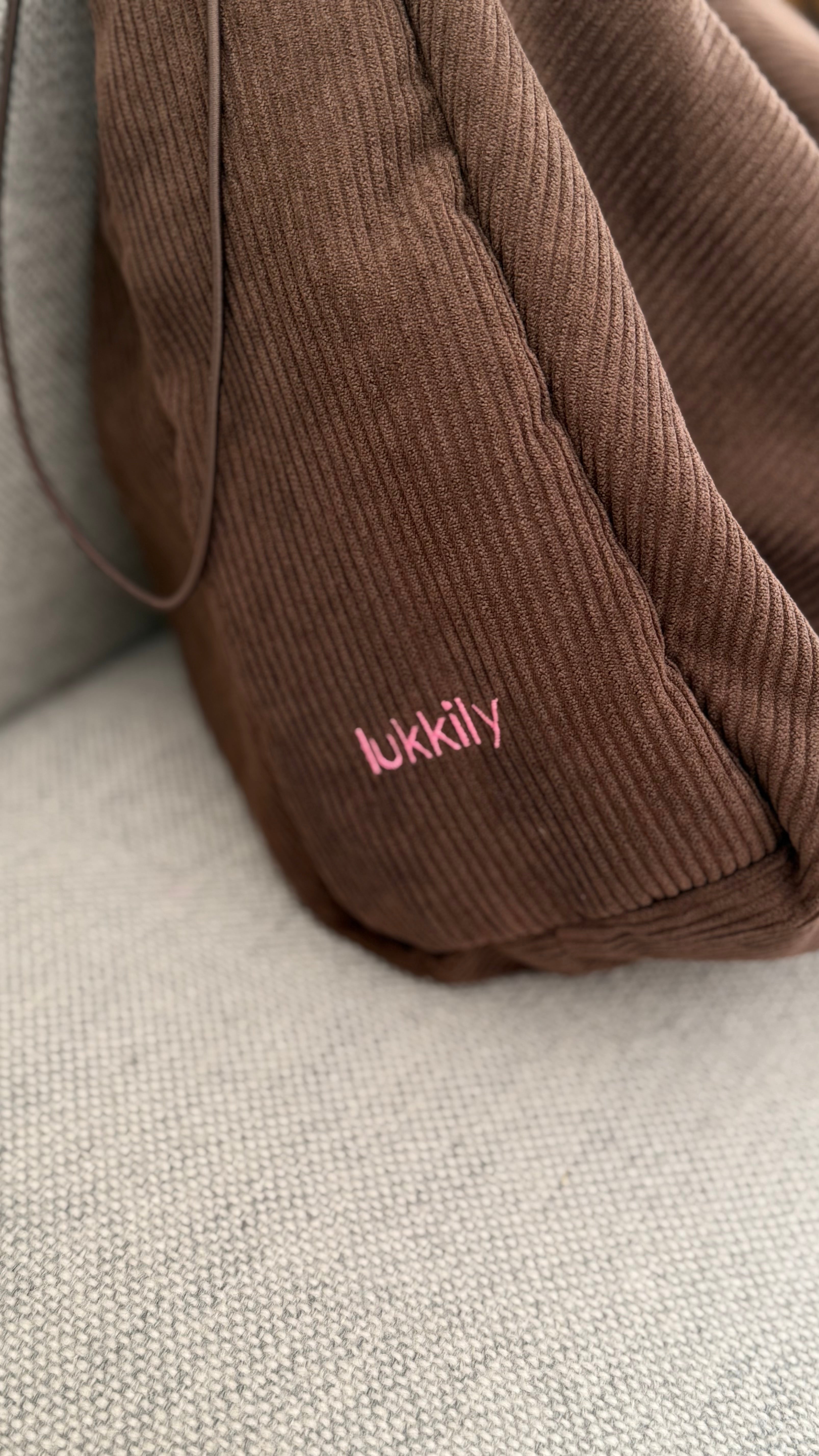 Detail der LUKKILY Ruffle Bag:  schokoladenbrauner Cordstoff mit feiner Rippenstruktur und pinken LUKKILY Logo.
