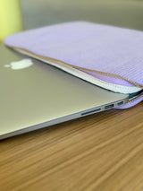 MacBook wird in eine gepolsterte Laptophülle aus Cord in Pastelllila geschoben – weicher Schutz für unterwegs mit Reißverschluss.