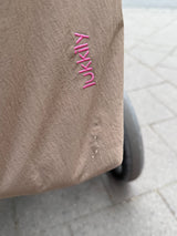 Nahaufnahme der pinken Lukkily Logo Stickerei sowie des Nylonmaterials, dessen wasserabweisende Wirkung hier zu sehen ist