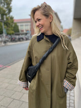 Detailaufnahme des gedrehten Highlighthenkels der schwarzen Mombag aus Glattleder, hier crossbody getragen
