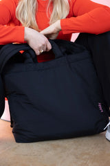 lukkily Gründerin Eva hält die große Mom Bag aus sportlichem schwarzen Nylon mit dezenter rosapinker Logostickerei und schlichtem schwarzen Design