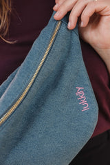 Lukkily Belt Bag Denim - Detailaufnahme des Jeansstoffs mit pinker lukkily Logo Stickerei und goldenem Reißverschluss