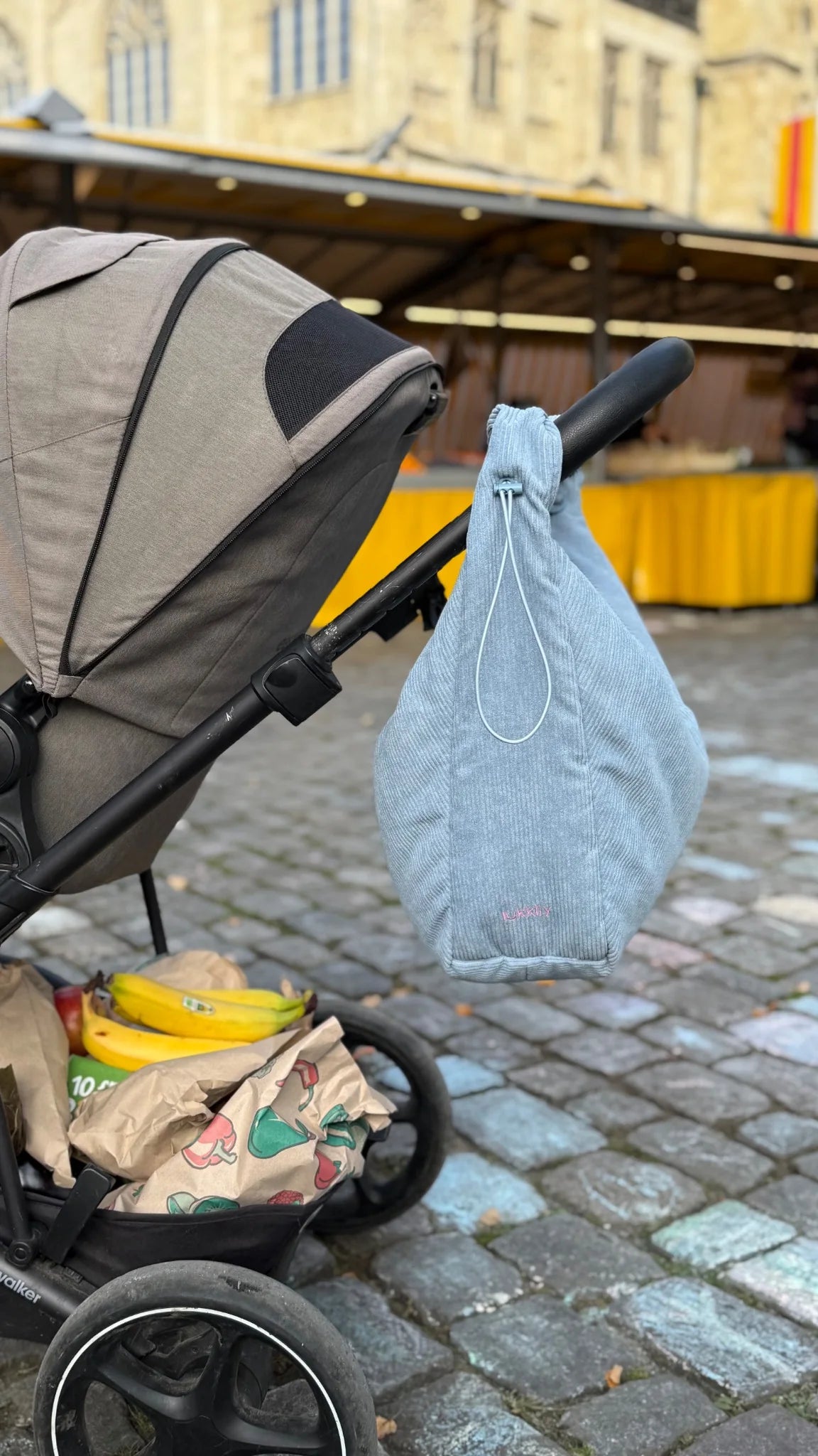 Sportive Cordtasche in hellblau als Mombag am Kinderwagen auf dem Markt