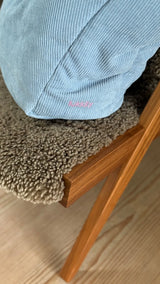 Detailaufnahme des gestickten pinken Lukkily Logos als schönes Designelement auf der hellblauen Cordtasche mit raffbarem Henkel