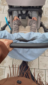 Mombag aus hellblauem Cord mit gerafftem Henkel am Kinderwagen, der von einer stylichen Mama geschoben wird