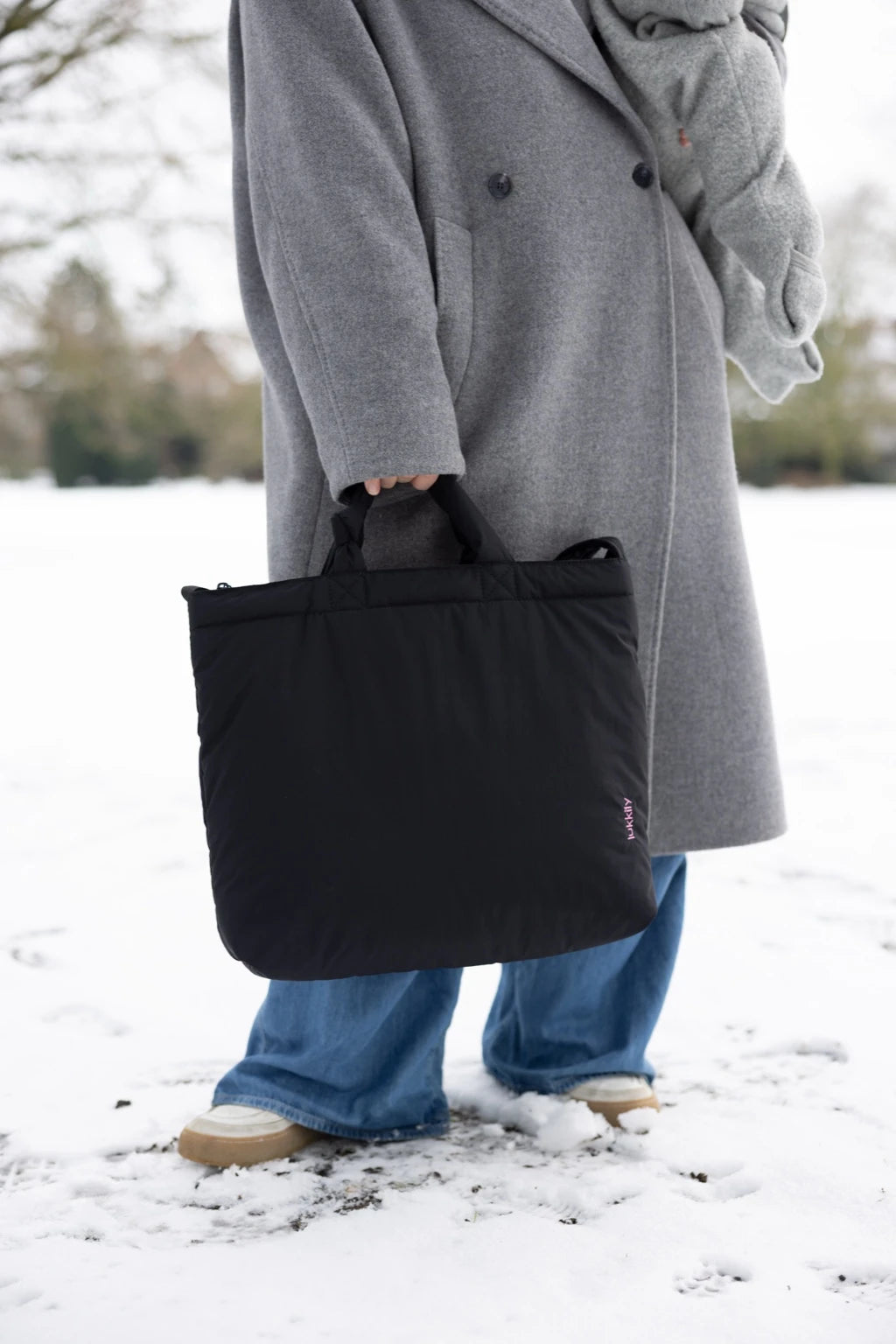 XXL Tote Bag aus schwarzem Nylon von Lukkily mit pinker Logo-Stickerei wird an den Henkeln getragen