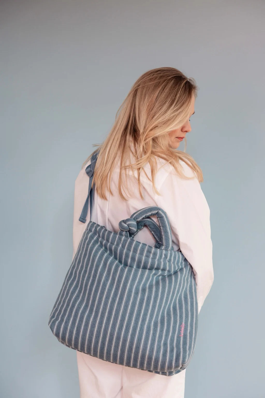 Gestreifte Wickeltasche aus Jeansstoff mit Reißverschluss und längenverstellbarem Schultergurt - getragen als Alltagstasche 