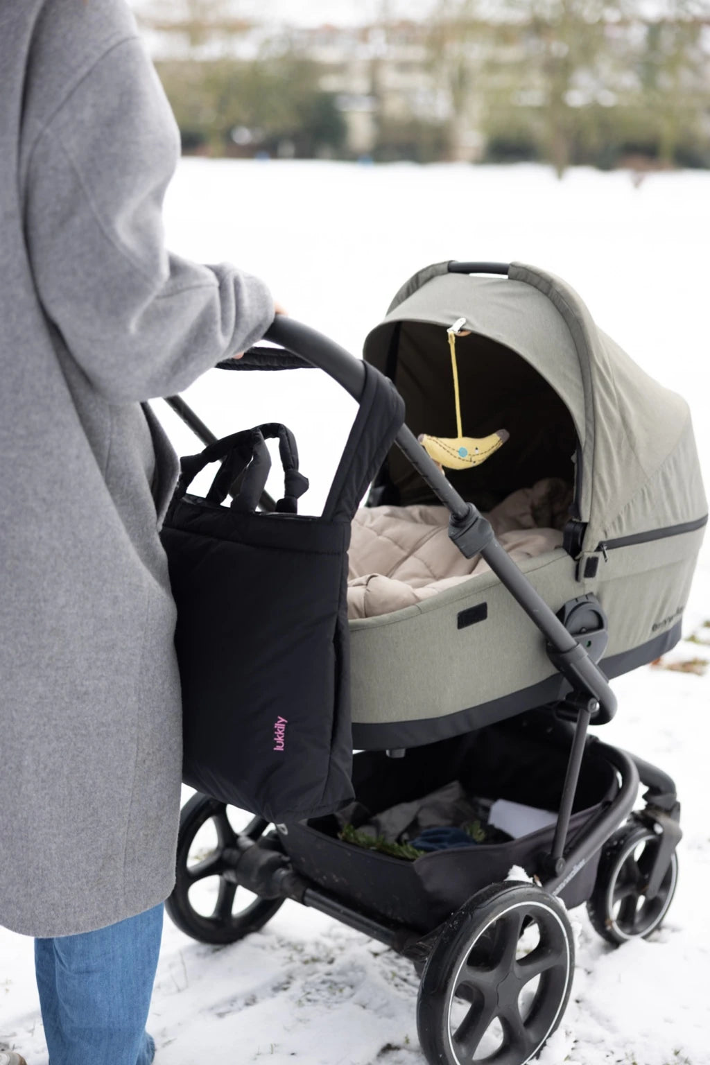 XXL Kinderwagentasche aus schwarzem Nylon von Lukkily mit Reißverschluss und pinker Logo-Stickerei hängt am Kinderwagen und passt an alle gängigen Kinderwagenmodelle